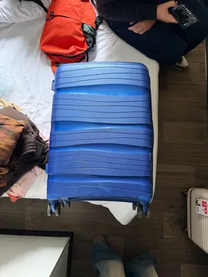 Grande valise rigide bleue à 4 roues en bon état, quelques rayures