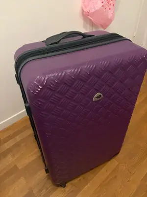 Grande valise violette en bon état, roulette qui accroche et traces d’usage